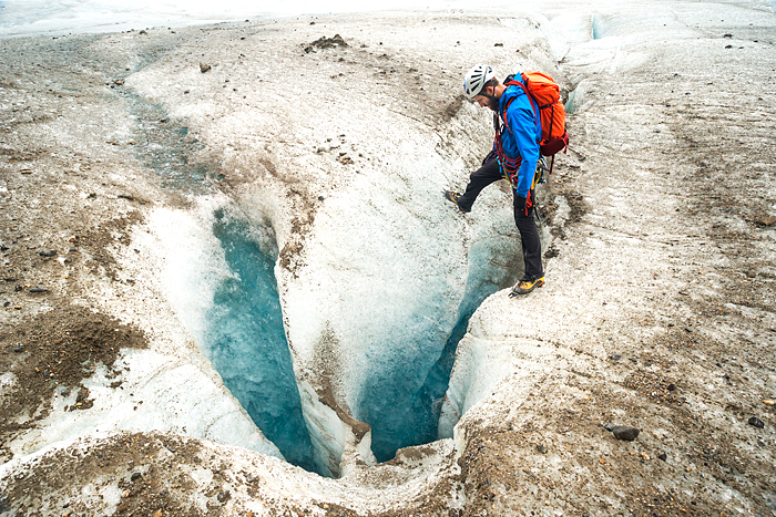 Guide looks into a deep crevasse on Lemon Glacier, Juneau Icefield, Juneau, Alaska, USA