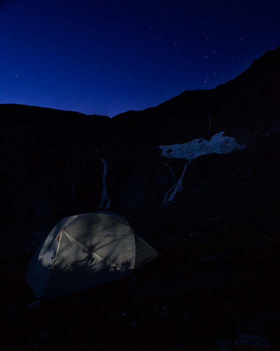 Night stars over waterfalls and tent on Lemon Glacier, Juneau Icefield, Juneau, Alaska, USA