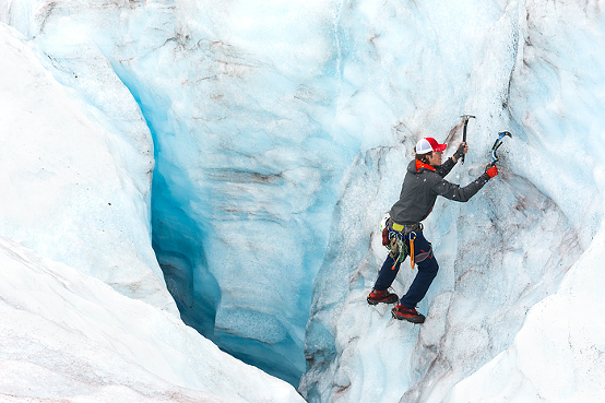 man ice climbing into huge crevasse on Lemon Glacier, Campsite of tent in glacier valley with mineral lake and waterfall at Lemon Glacier, Juneau Icefield, Juneau, Alaska, USA