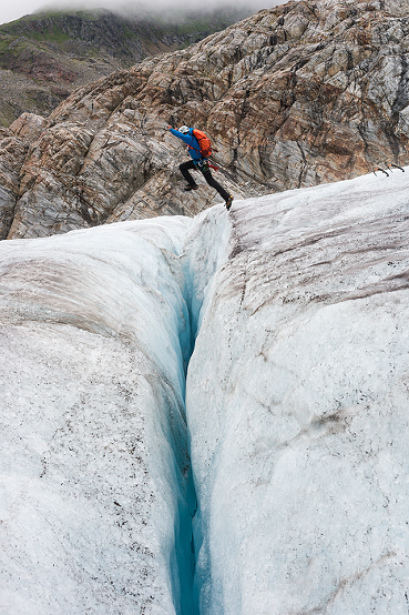 Man jumps over crevasse while trekking adventure on Lemon Glacier, Juneau Icefield, Juneau, Alaska, USA