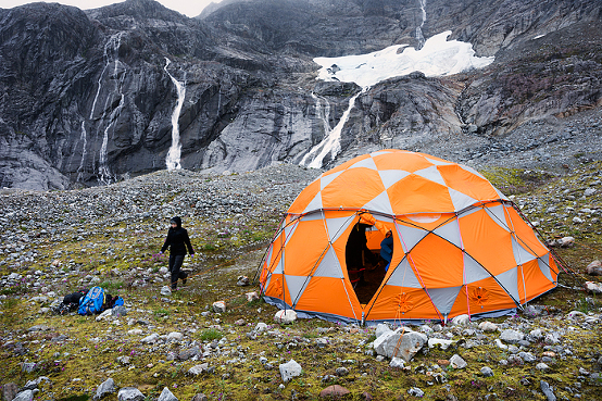 Campsite of tent in glacier valley with mineral lake and waterfall at Lemon Glacier, Juneau Icefield, Juneau, Alaska, USA