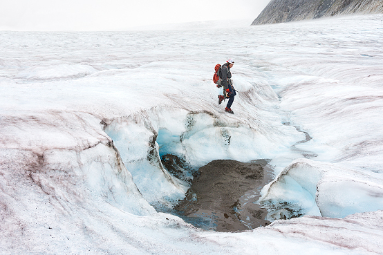 Man jumps over crevasse while trekking adventure on Lemon Glacier, Juneau Icefield, Juneau, Alaska, USA