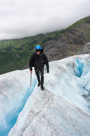 man straddles crevasses in Alaska