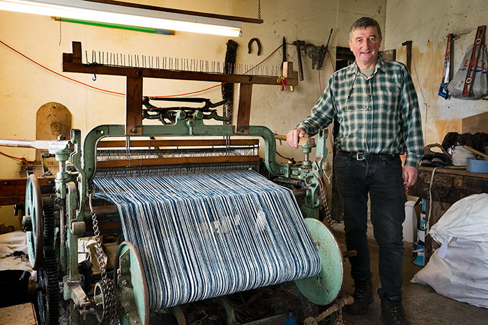 Harris Tweed weaver beside old loom on the Isle of Lewis