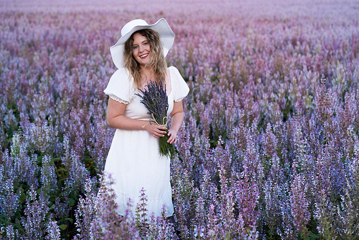 Clary sage, Pretty blond woman in a white dress walks through a blooming field, Valensole, Provence, France